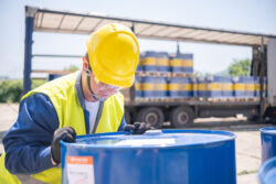 A warehouse worker manually adjusts drums of motor oil.