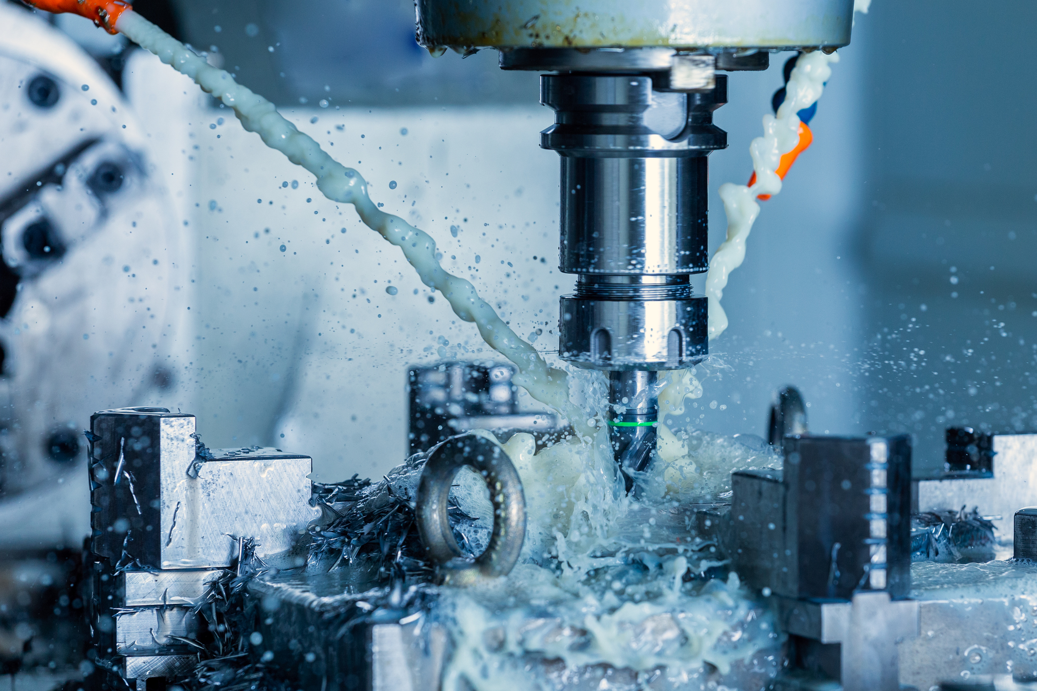 A process of vertical cnc steel milling with external water coolant streams, splashes and a lot of metal chips. Fast shutter speed for motion freezing.