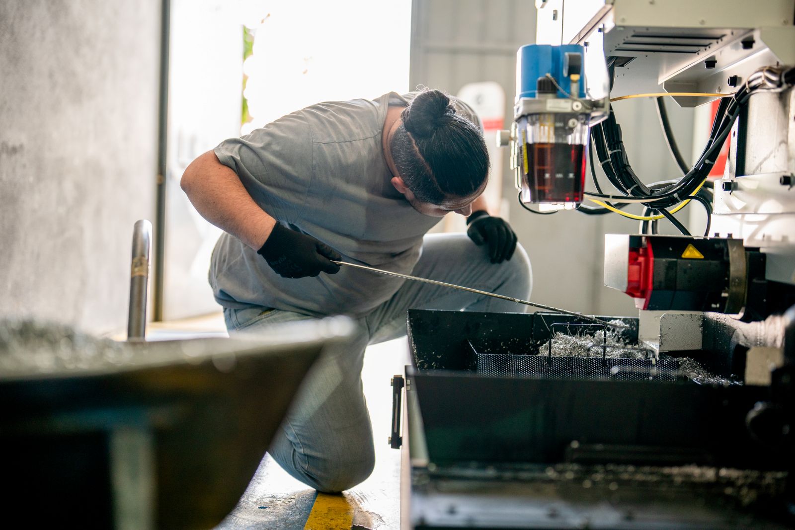 A warehouse worker manually adjusts drums of motor oil.
